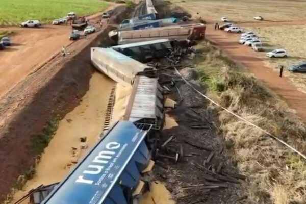 Descarrilamento em Araraquara: Trem de Carga Colide com Caminhão e Deixa 14 Vagões Fora dos Trilhos Vagões de trem de carga descarrilados e tombados ao lado da linha férrea, com milho espalhado no chão, após colisão com caminhão.