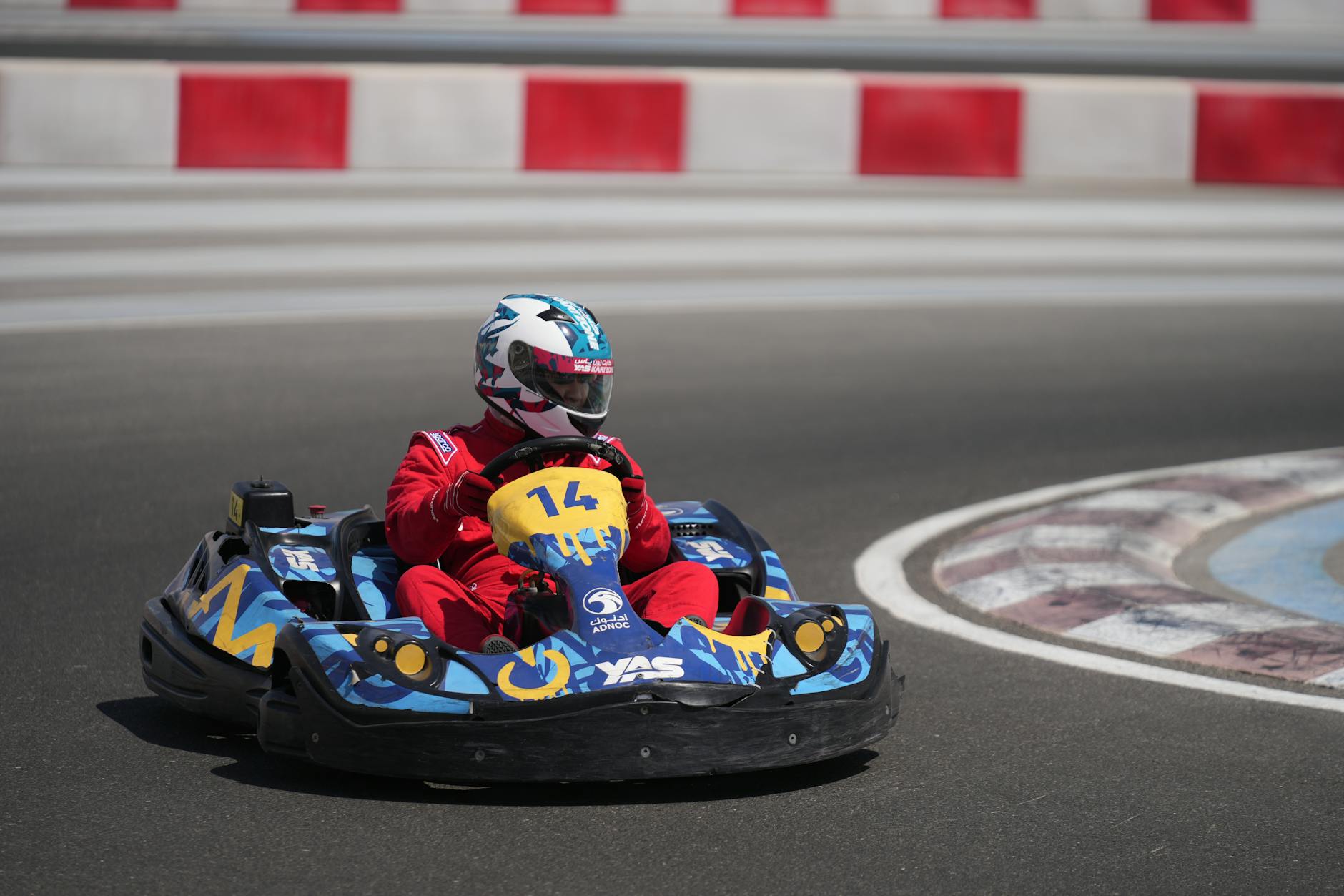 A go-kart racer in red suit speeds on Yas Marina Circuit in Abu Dhabi.