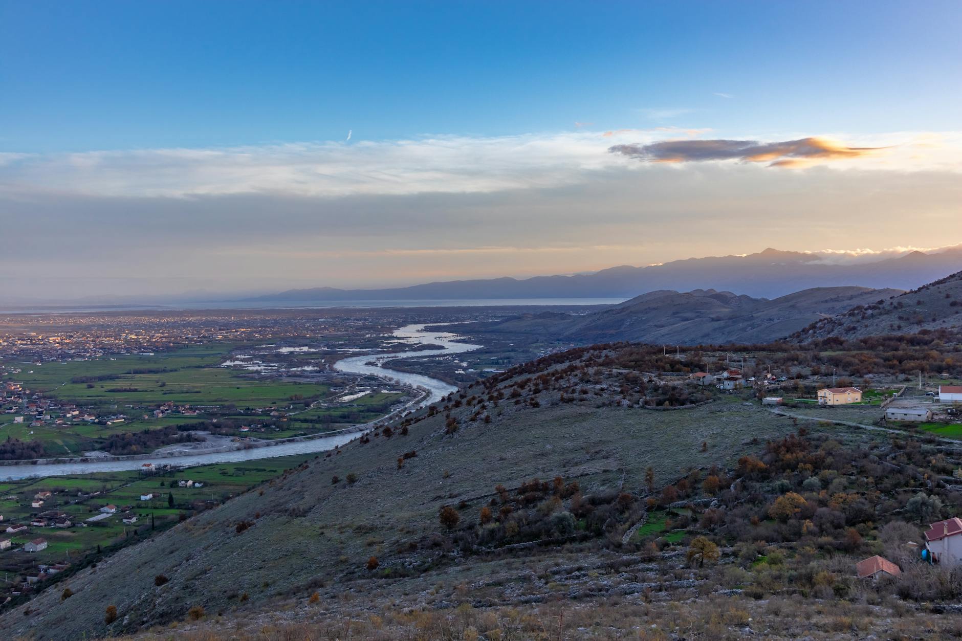 Beautiful landscape of Podgorica, Montenegro, showcasing a river meandering through the valley at sunset.