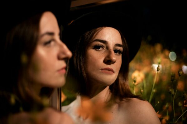 SP: Cadeias Superlotadas Aumentam Risco de Rebeliões A captivating portrait of a woman with a mirror reflection, featuring vibrant floral background.