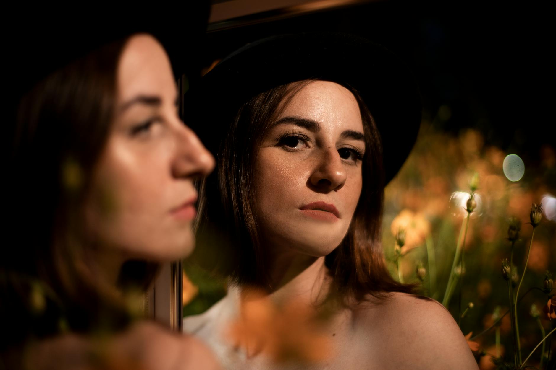 A captivating portrait of a woman with a mirror reflection, featuring vibrant floral background.