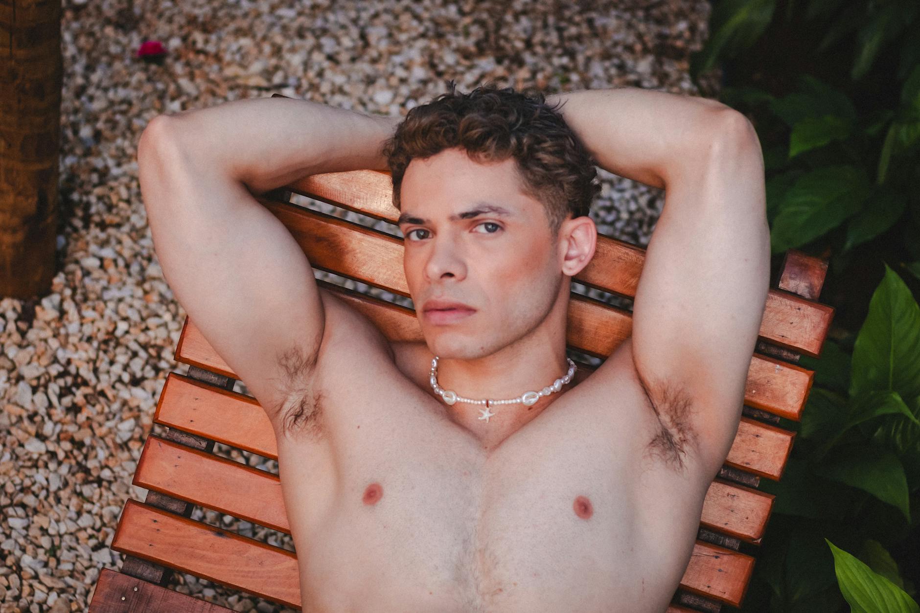 A man lounges on a wooden chair outdoors in São Paulo, Brazil, showcasing a serene and confident expression.