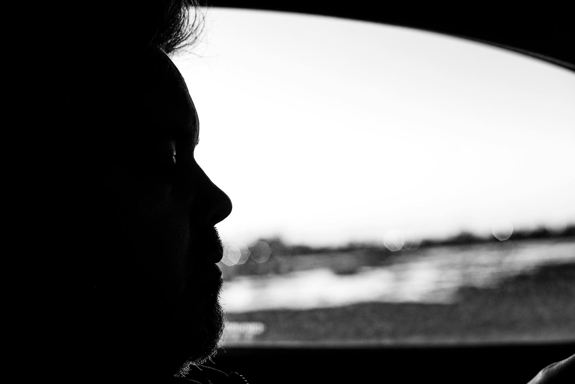 Artistic silhouette of a person inside a car during twilight captures urban essence.