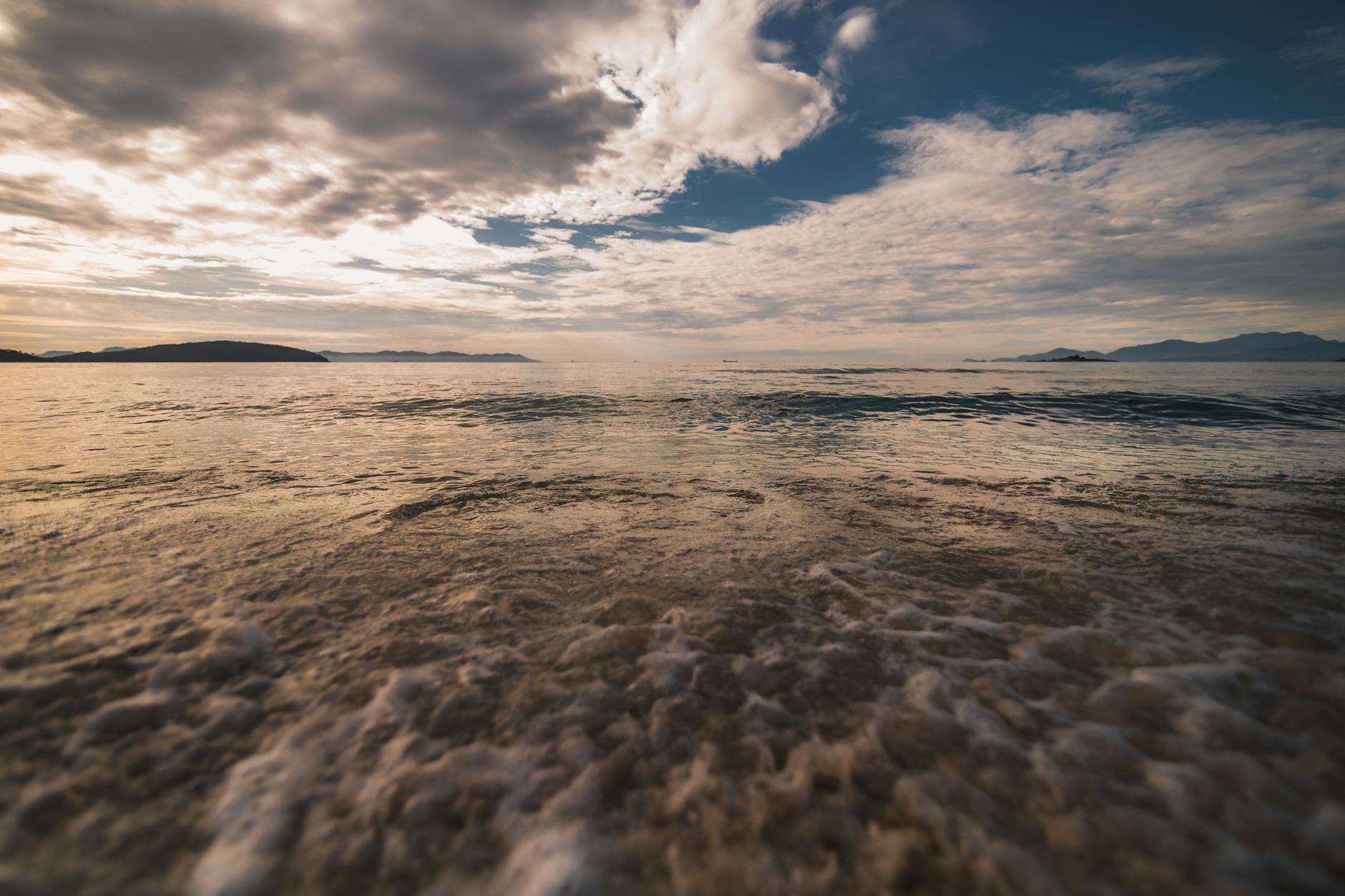 Calm ocean waves at Angra dos Reis, Brazil, with a stunning sunset sky.