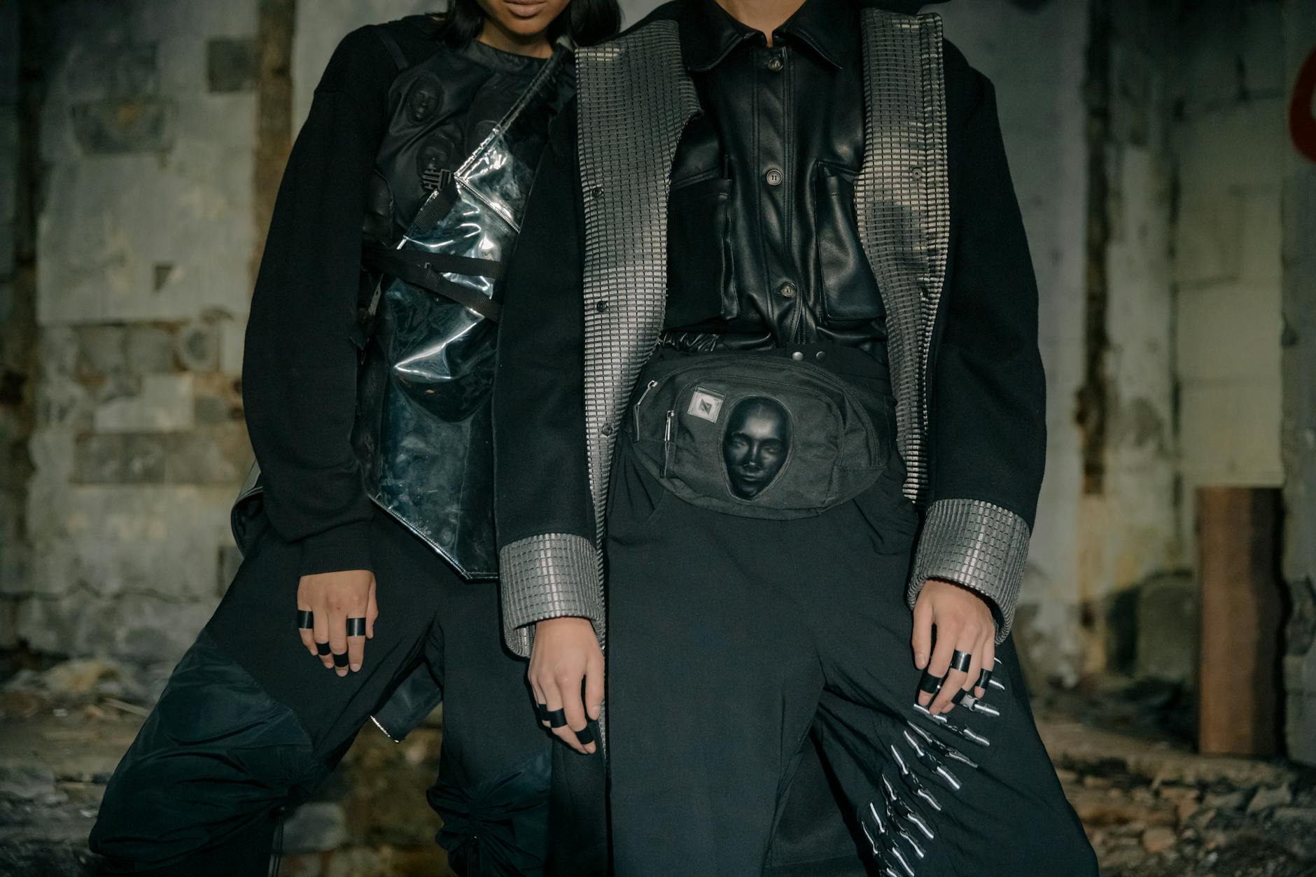 Two models in edgy cyberpunk attire pose in an industrial setting.