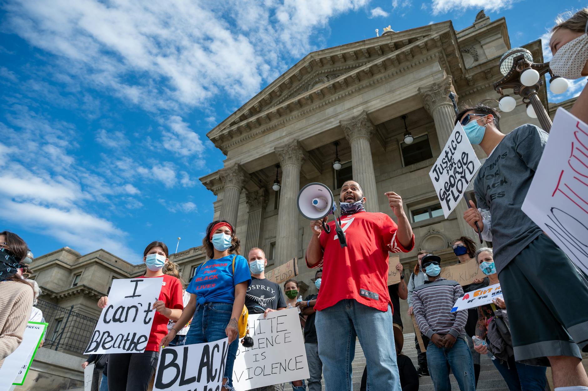 Protesters advocating for racial justice with signs and masks outdoors.