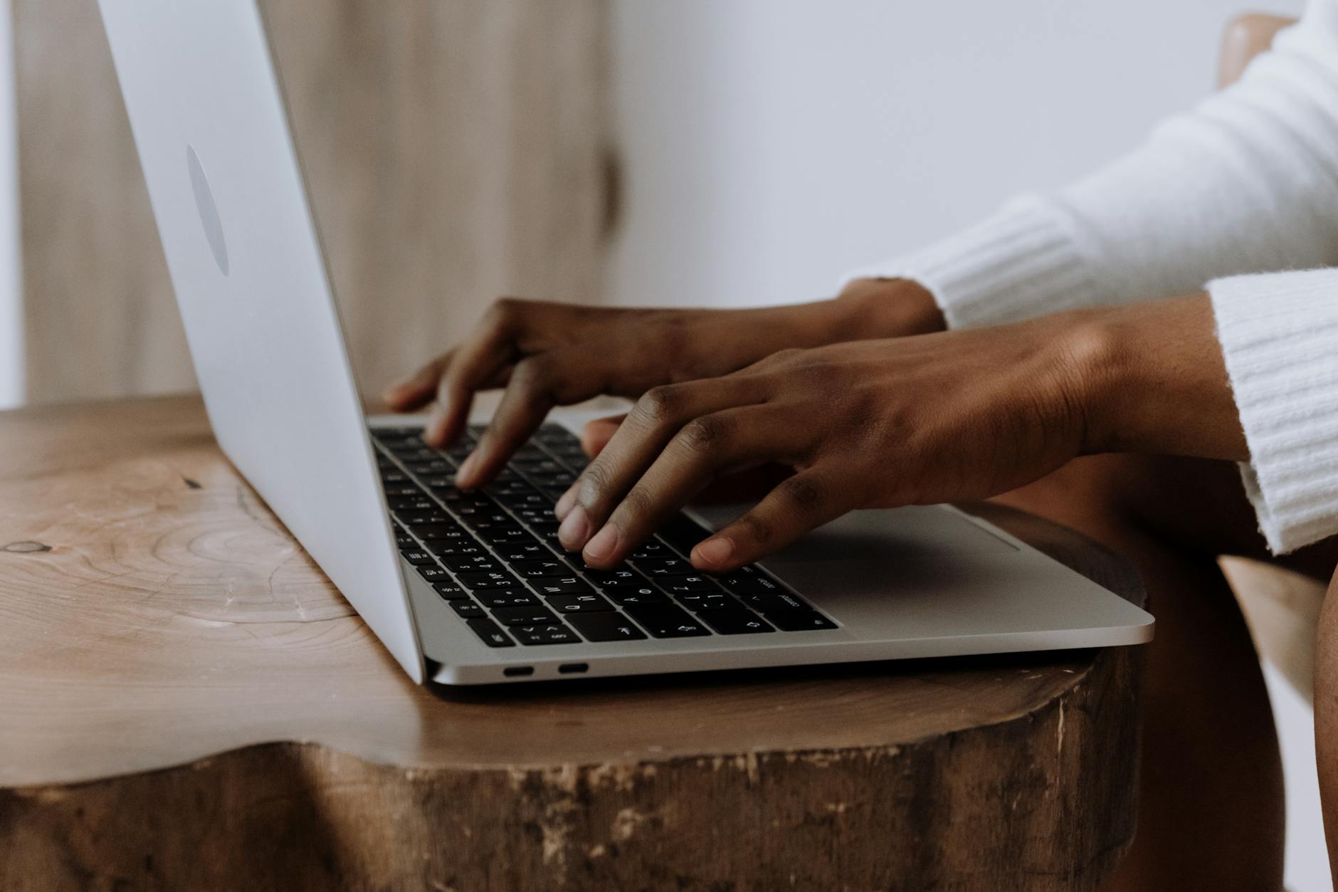 Hands typing on a laptop in a cozy indoor setting, focusing on technology and digital work.