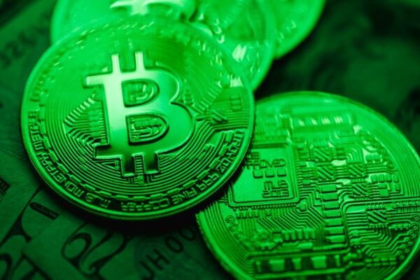 Tribunal inova ao usar blockchain em registro de fianças Close-up of green-illuminated Bitcoin coins representing digital currency and blockchain technology.