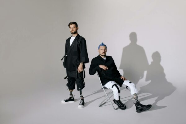 Two fashionable men with prosthetic limbs in modern attire, showcasing a futuristic look.