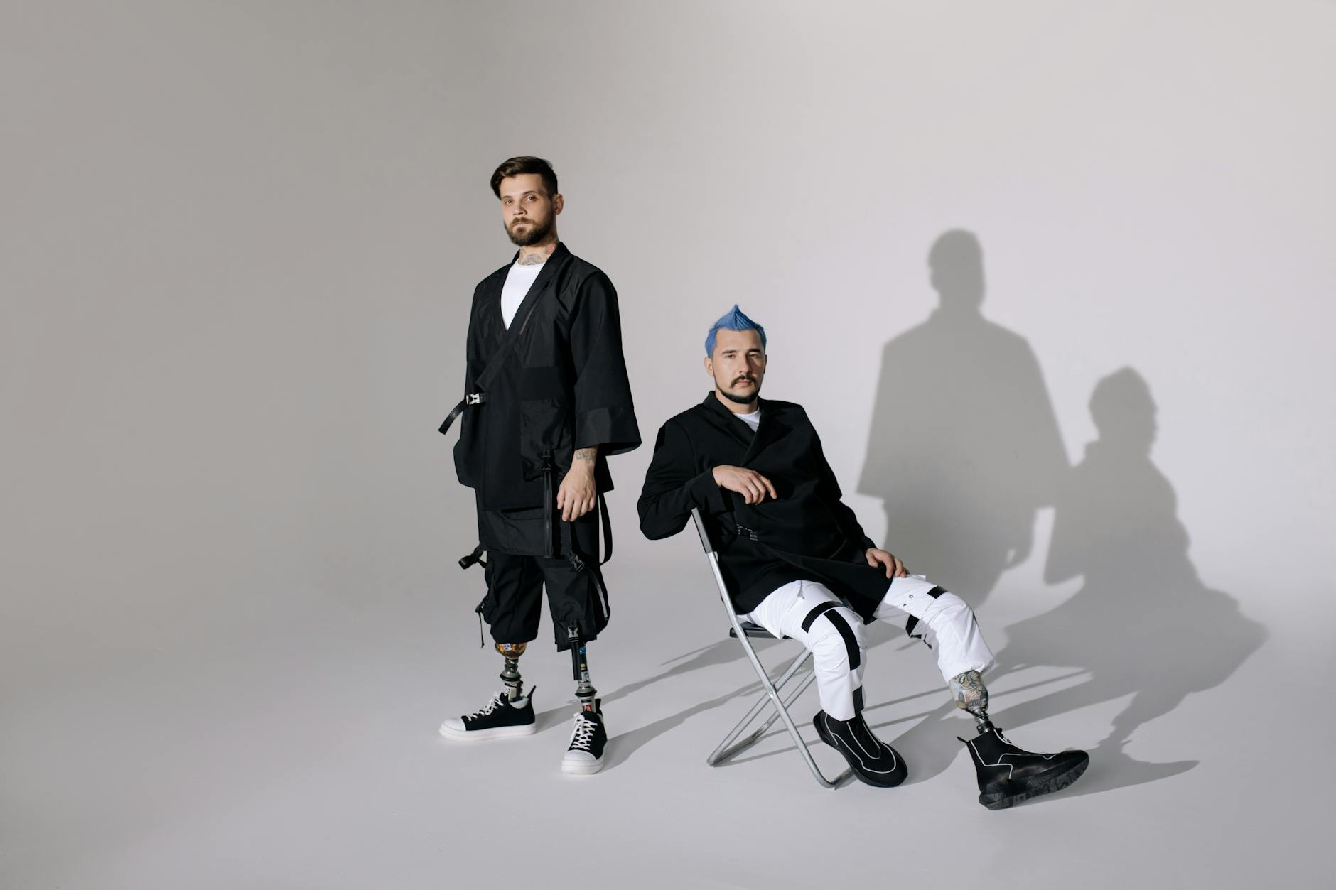 Two fashionable men with prosthetic limbs in modern attire, showcasing a futuristic look.