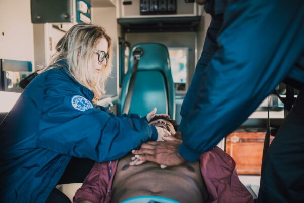 Emergency responders performing CPR on patient in ambulance setting.
