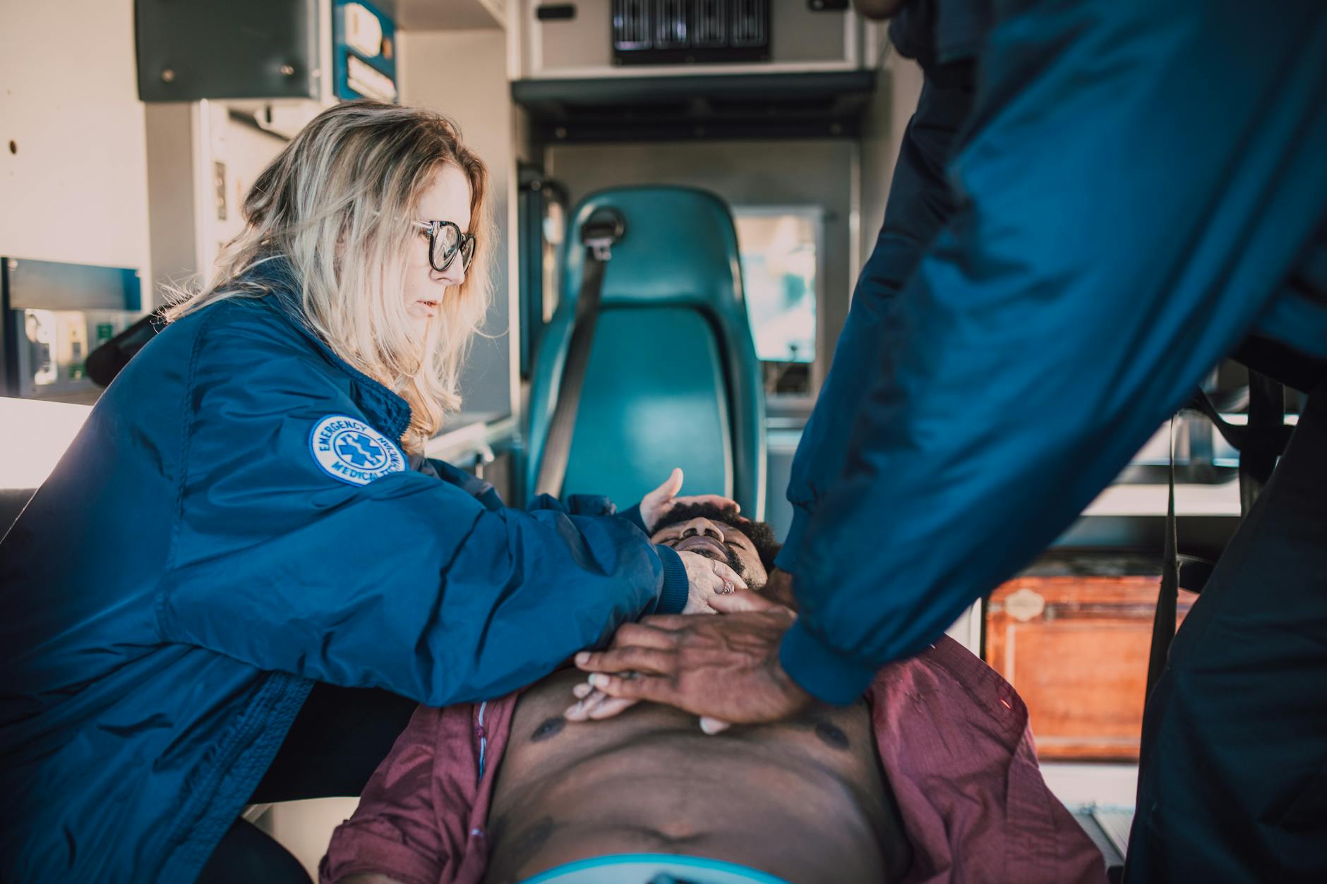 Emergency responders performing CPR on patient in ambulance setting.
