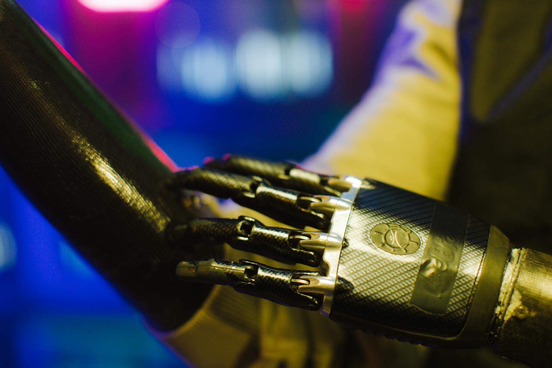 Close-up of a sleek prosthetic hand interacting with a robotic arm in a high-tech environment.