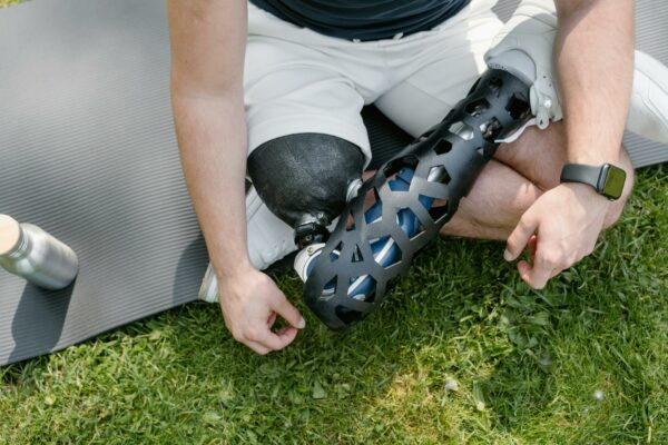 Inteligência Artificial Acelera Análise de Imagens em Inquéritos Close-up of a person with a prosthetic leg sitting on grass with exercise mat, embracing a healthy lifestyle.