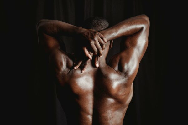 STJ Define Critérios para Prisão Domiciliar de Dependentes Químicos Strong men with defined muscles stretching his back and arms against a dark background.