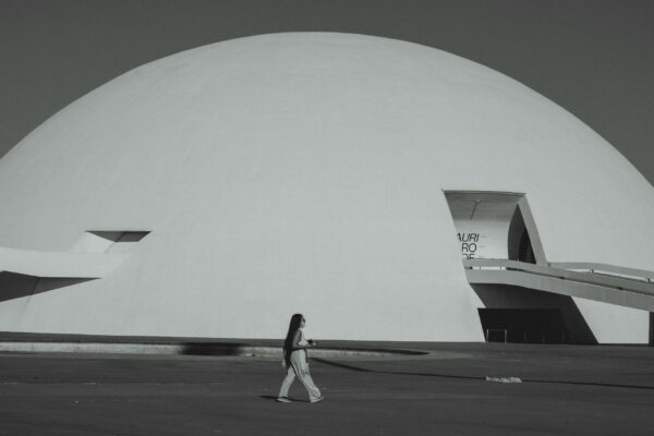Polícia Desmantela Esquema de Pirâmide Financeira com Criptomoedas A woman walks by the futuristic Niemeyer Dome in Brasília, showcasing modern architecture.