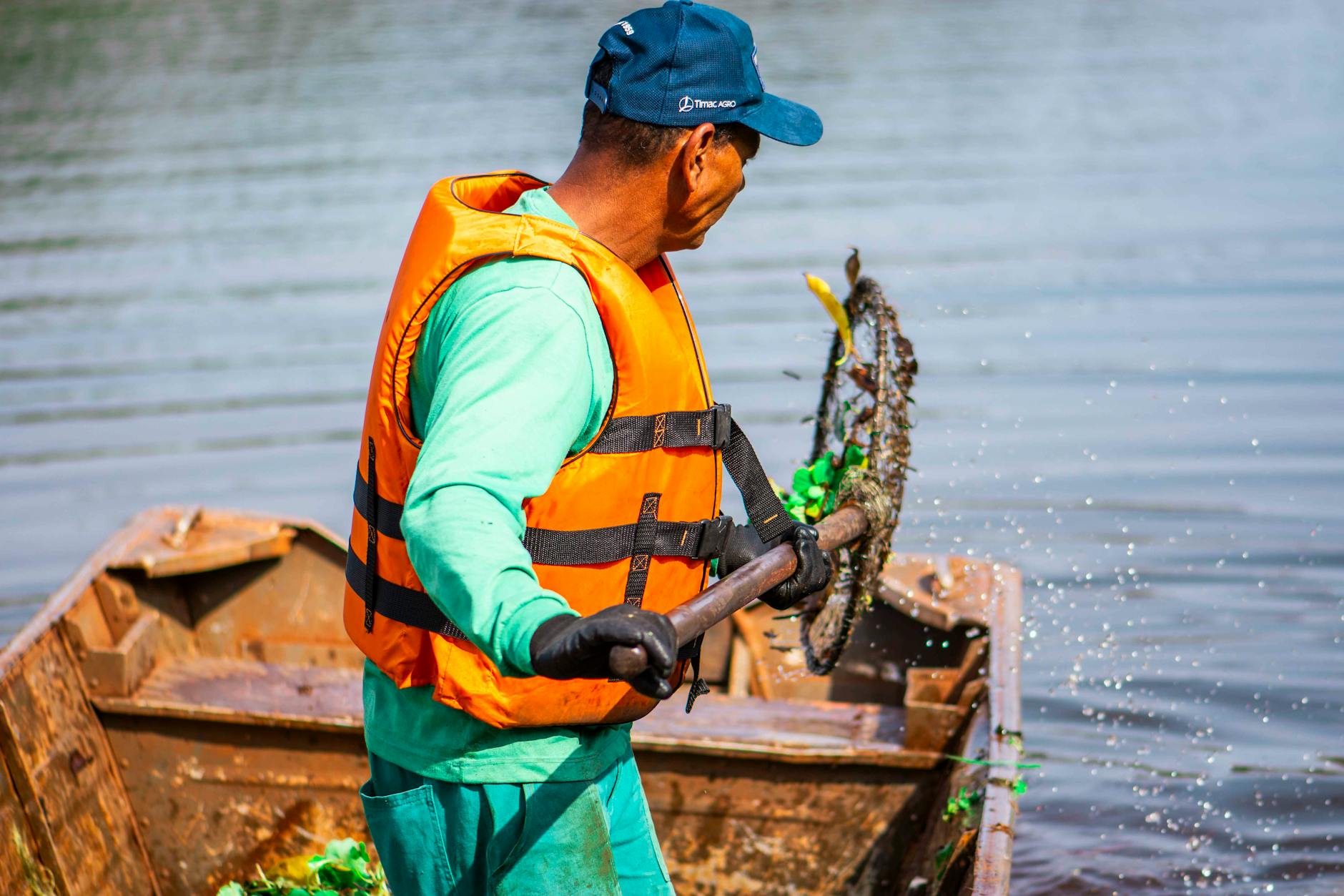 A worker cleaning a lake in Londrina, Brasil, wearing a life vest and using a net.