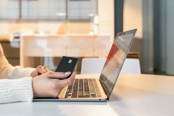 Crédito de Carbono Atrai Investimento e Moderniza Setor Agrícola A woman using a credit card and laptop for online shopping in a modern indoor setting.