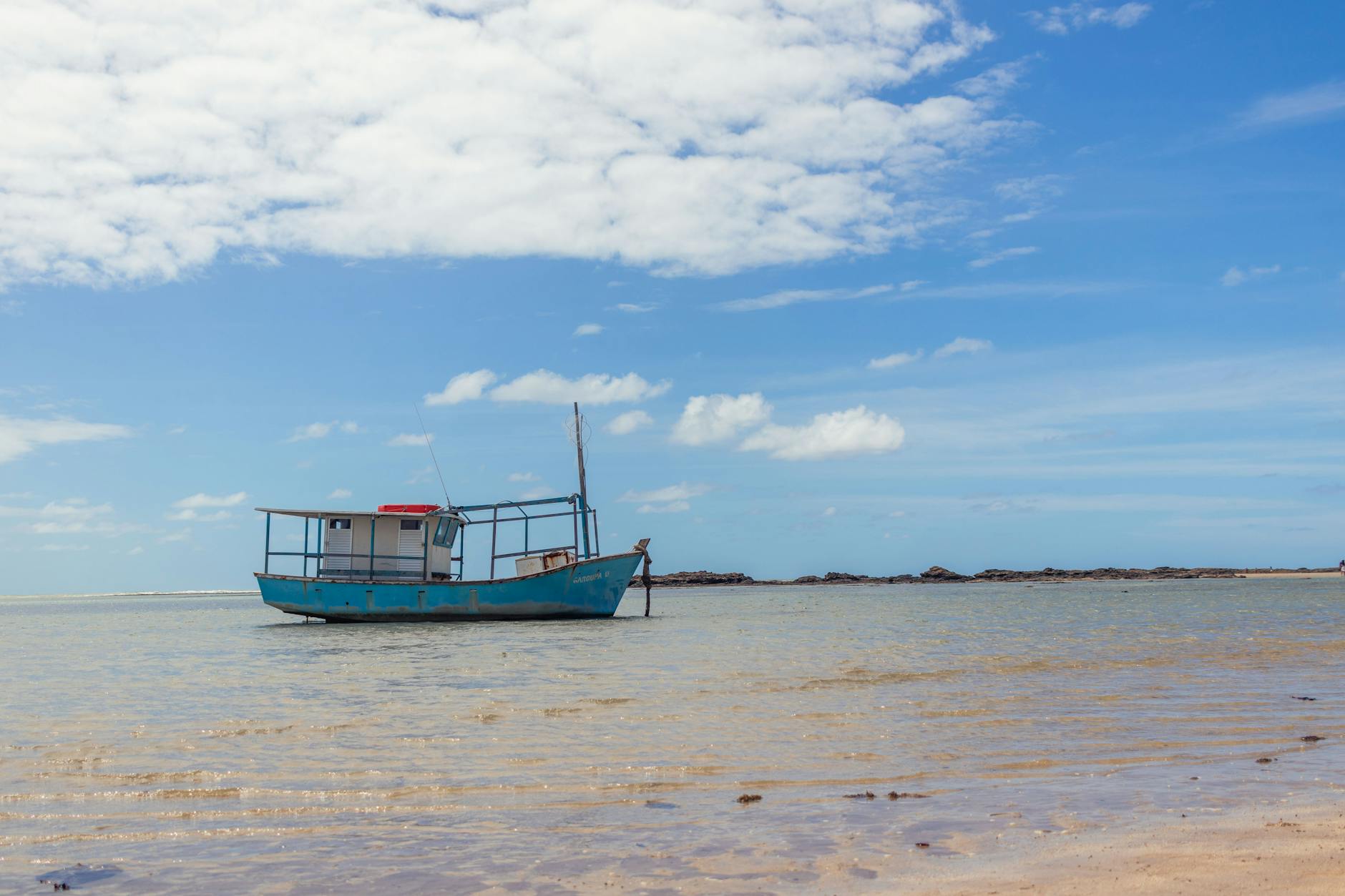 Serene view of a fishing boat on Morro de São Paulo beach in Bahia, Brazil under a clear blue sky.