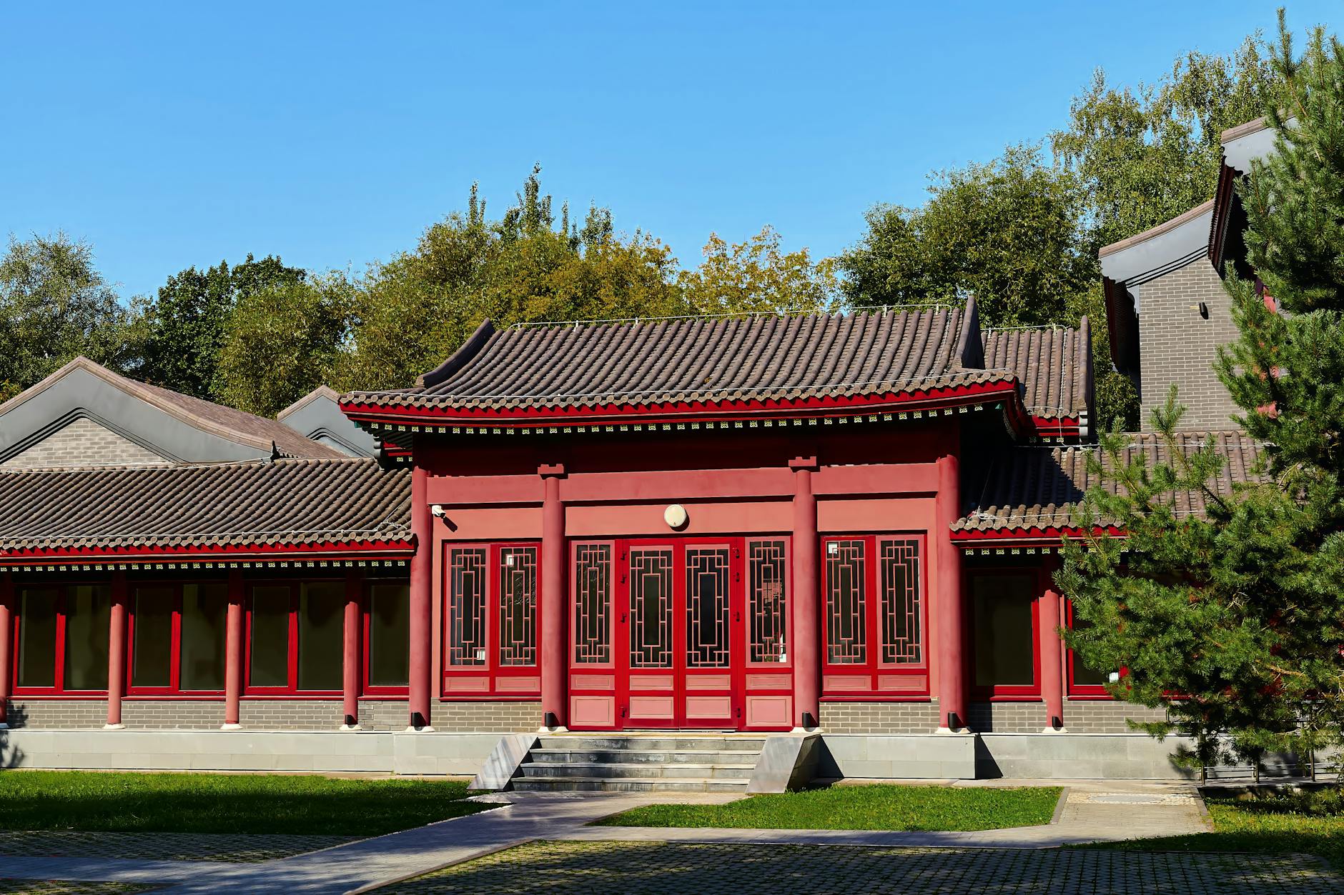 Explore a serene traditional Chinese building in a Moscow park, surrounded by lush greenery under a clear blue sky.