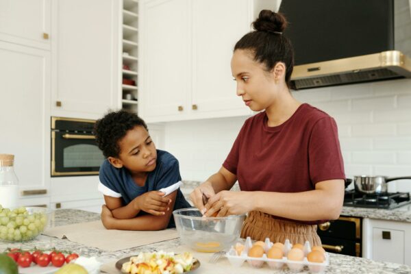 STF Decide Sobre Revisão de Benefícios do INSS Mother and son enjoying quality time preparing food in a modern kitchen setting.