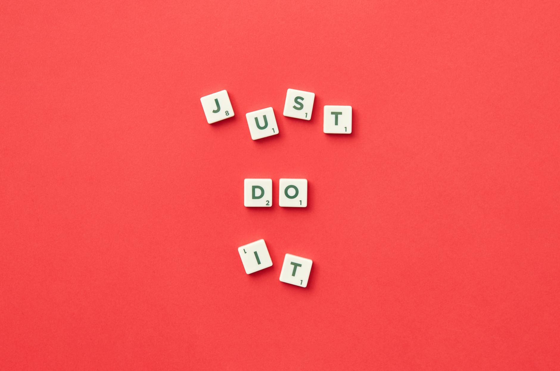 Motivational phrase 'Just Do It' spelled with Scrabble letters on a red background.