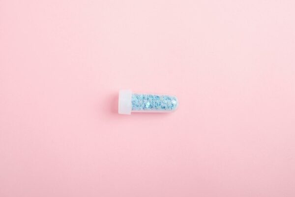 Viih Tube Revela Luta Pós-Parto Contra Queda Capilar Intensa Top view of tube full of shimmering blue glitter for design and decoration on pink background