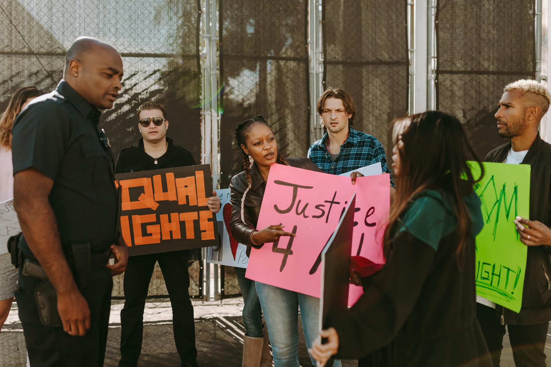 Protesters holding signs demand justice and equal rights in street confrontation with a policeman.