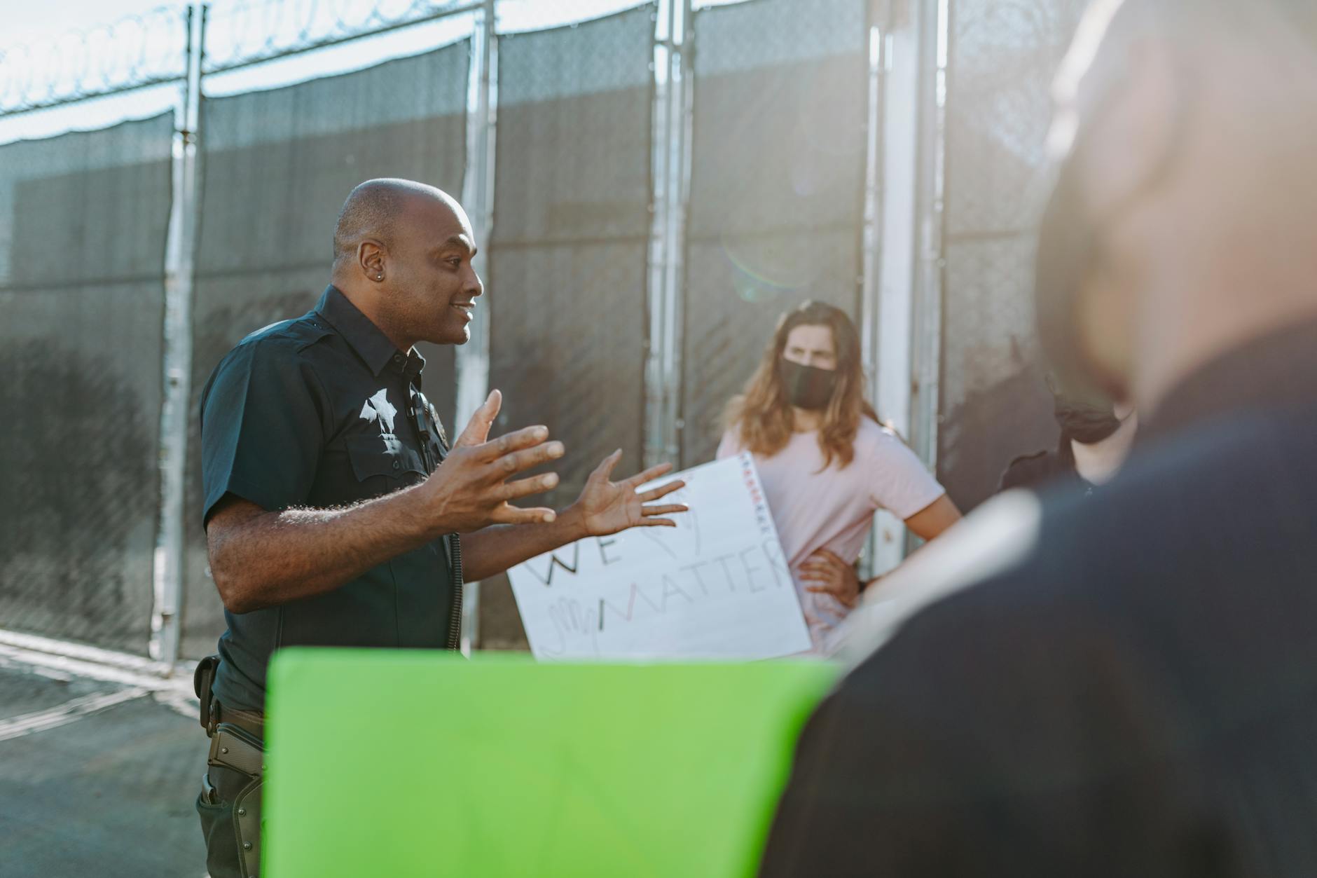 A police officer converses with protesters holding signs outdoors, demonstrating active communication.