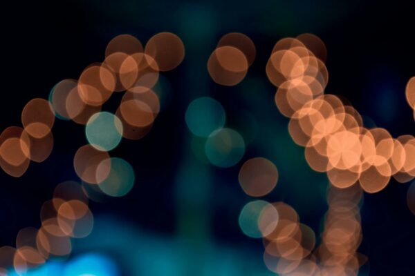 TJRS Determina Gratuidade de Crematórios para Carentes Abstract bokeh light patterns in vibrant orange and teal hues create an artistic effect.