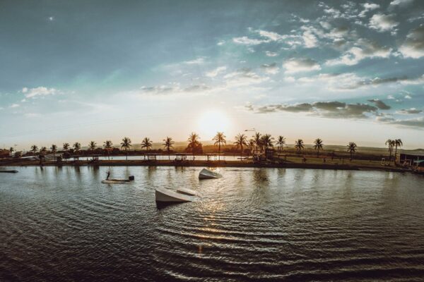 Golpe do Leilão Falso Lesa Produtores Rurais em Goiás Beautiful sunset over a tranquil wakeboard park in Goiás, Brazil. Captivating palm tree silhouettes.